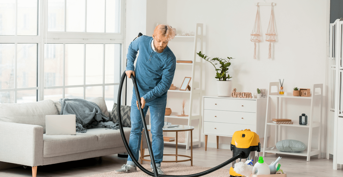 young man hoovering carpet home 3