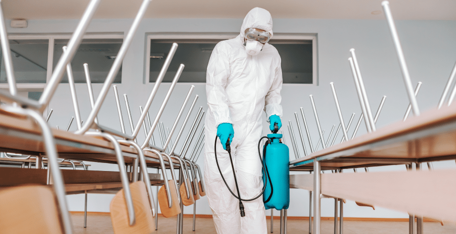 40aff4d5 man sterile uniform with gloves mask holding sprayer spraying with disinfectant floor classroom 1.png