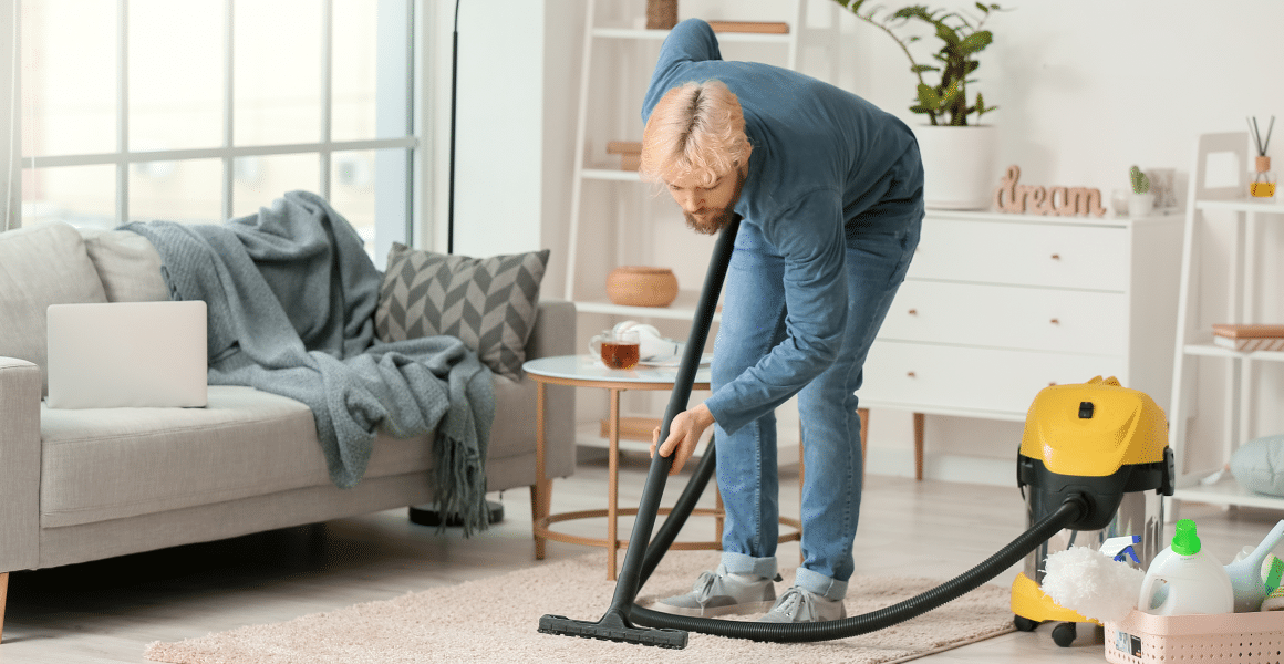 92108ec2 young man hoovering carpet home 1.png